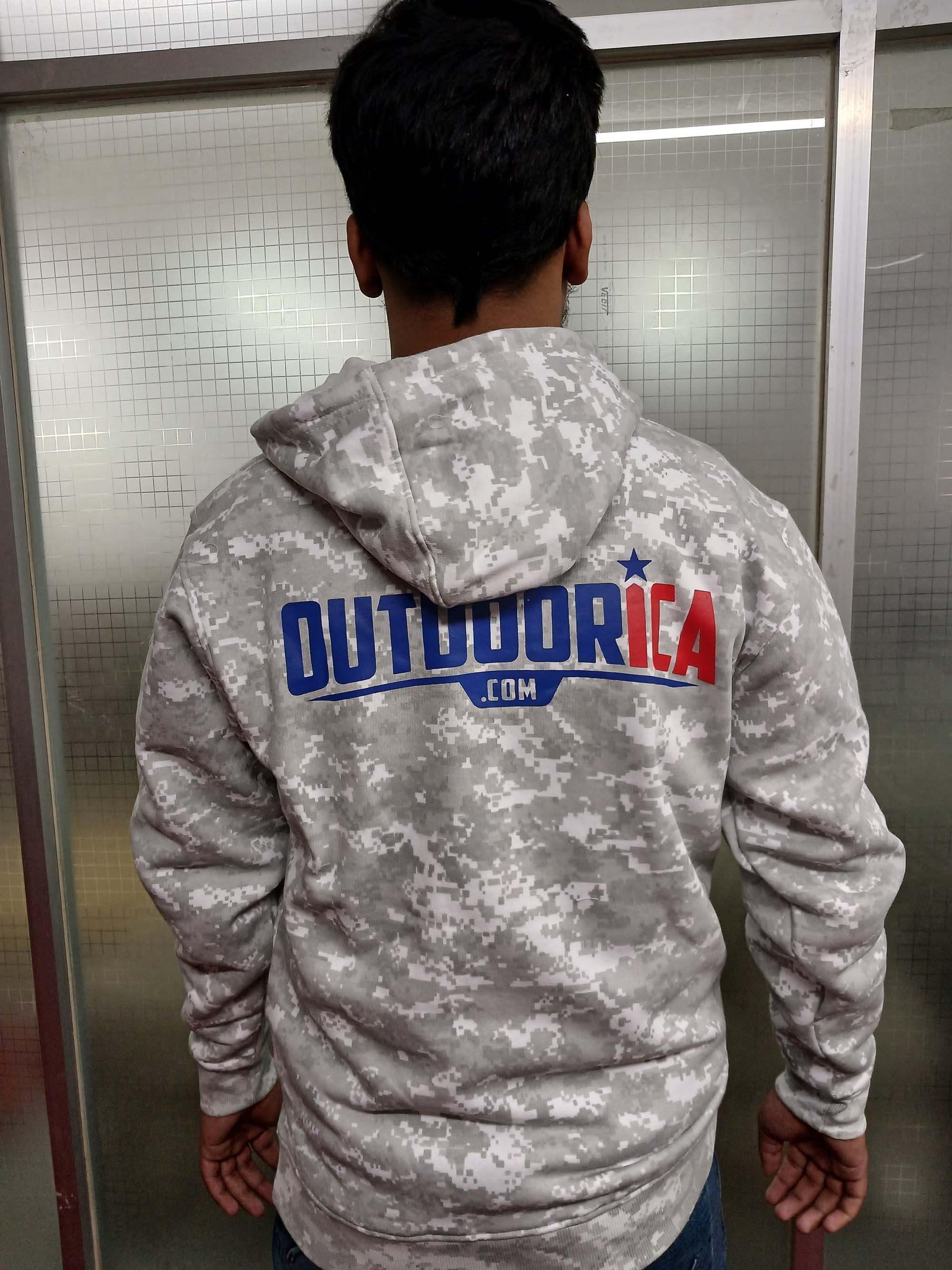 Young man wearing a light brown Realtree camouflage hunting hoodie in a natural setting.